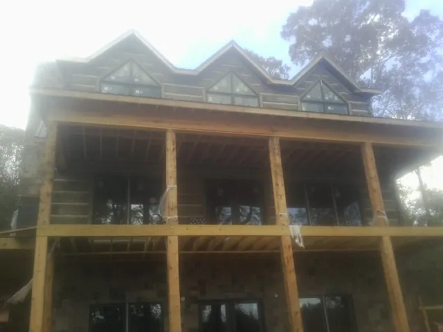 Dormers and porch framing on a large log home under construction — Roof Coating work by our crew in Clearwater Beach