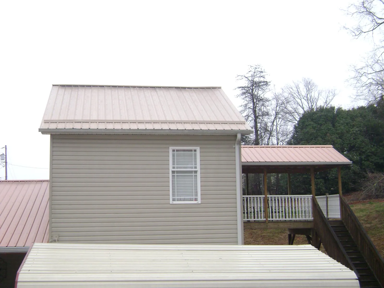 Tan metal roofs on a two story addition and attached porch, from a Roof Replacement job in Clearwater Beach