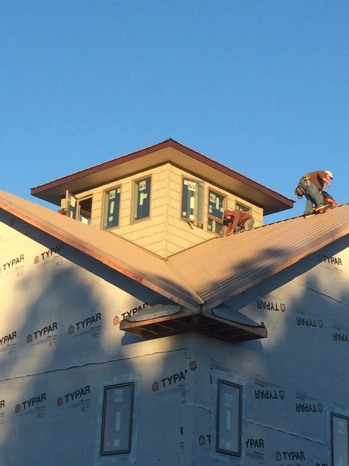 Roofers working around a rooftop cupola on a new metal roof at sunset — Roof Waterproofing in Clearwater Beach by Roofing Brothers